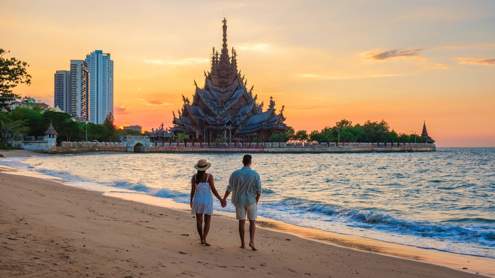 cuplu viziteaza templul de lemn The Sanctuary of Truth in Pattaya Thailanda la apus