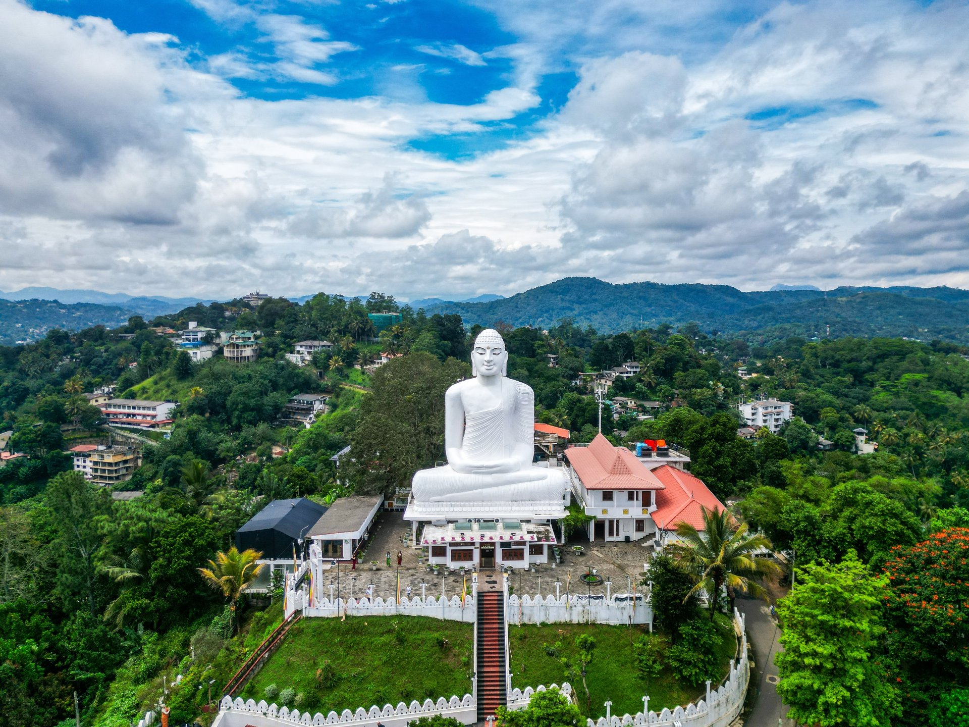 vedere aeriana asupra statuii uriase a lui Buddha din Kandy, Sri Lanka, inconjurata de munti verzi si peisaje tropicale, cu atmosfera linistita si cer senin