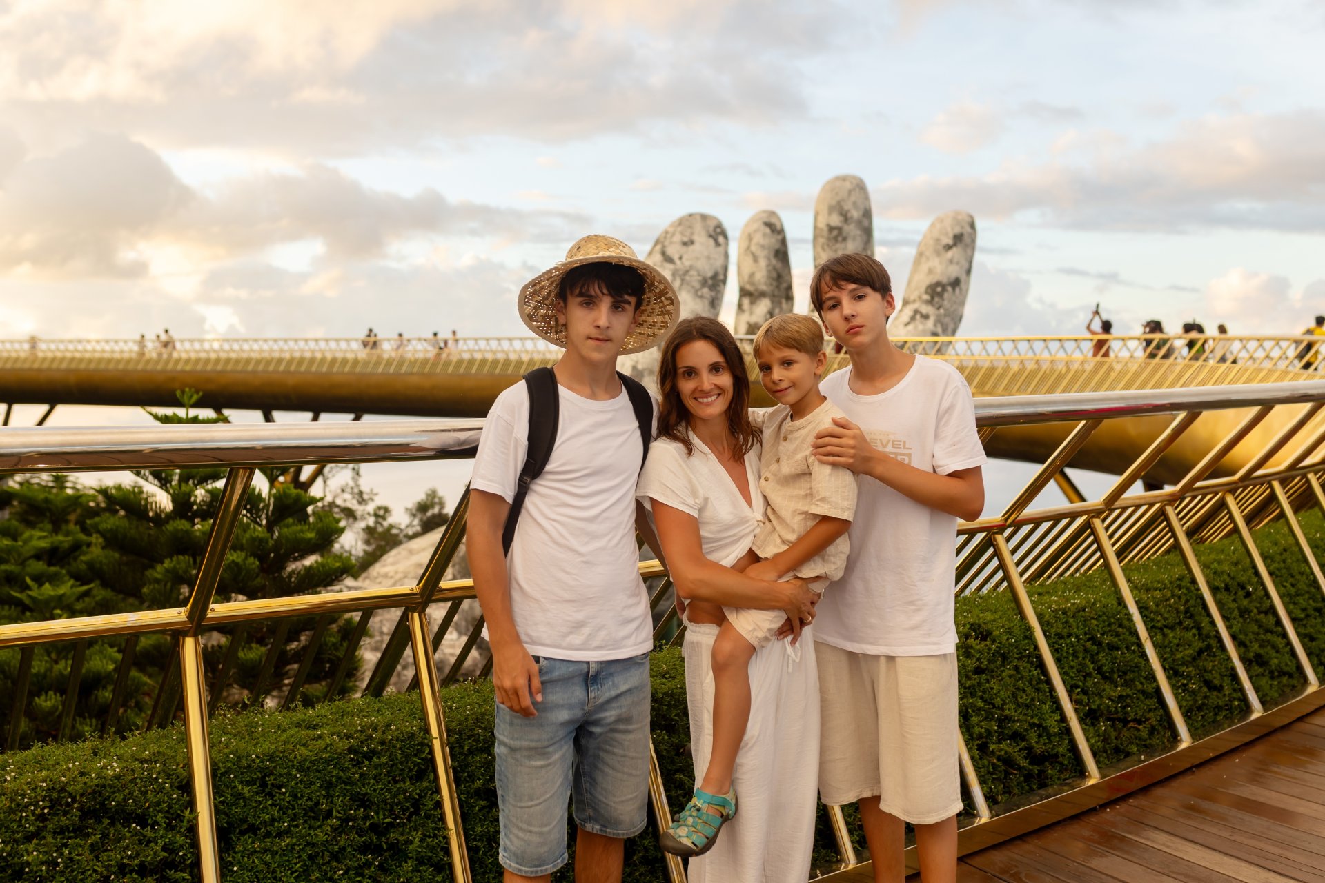 Familie cu copii viziteaza Golden Bridge sustinut de mainile de aur in Ba Na Hills Da Nang Vietnam la apus de soare