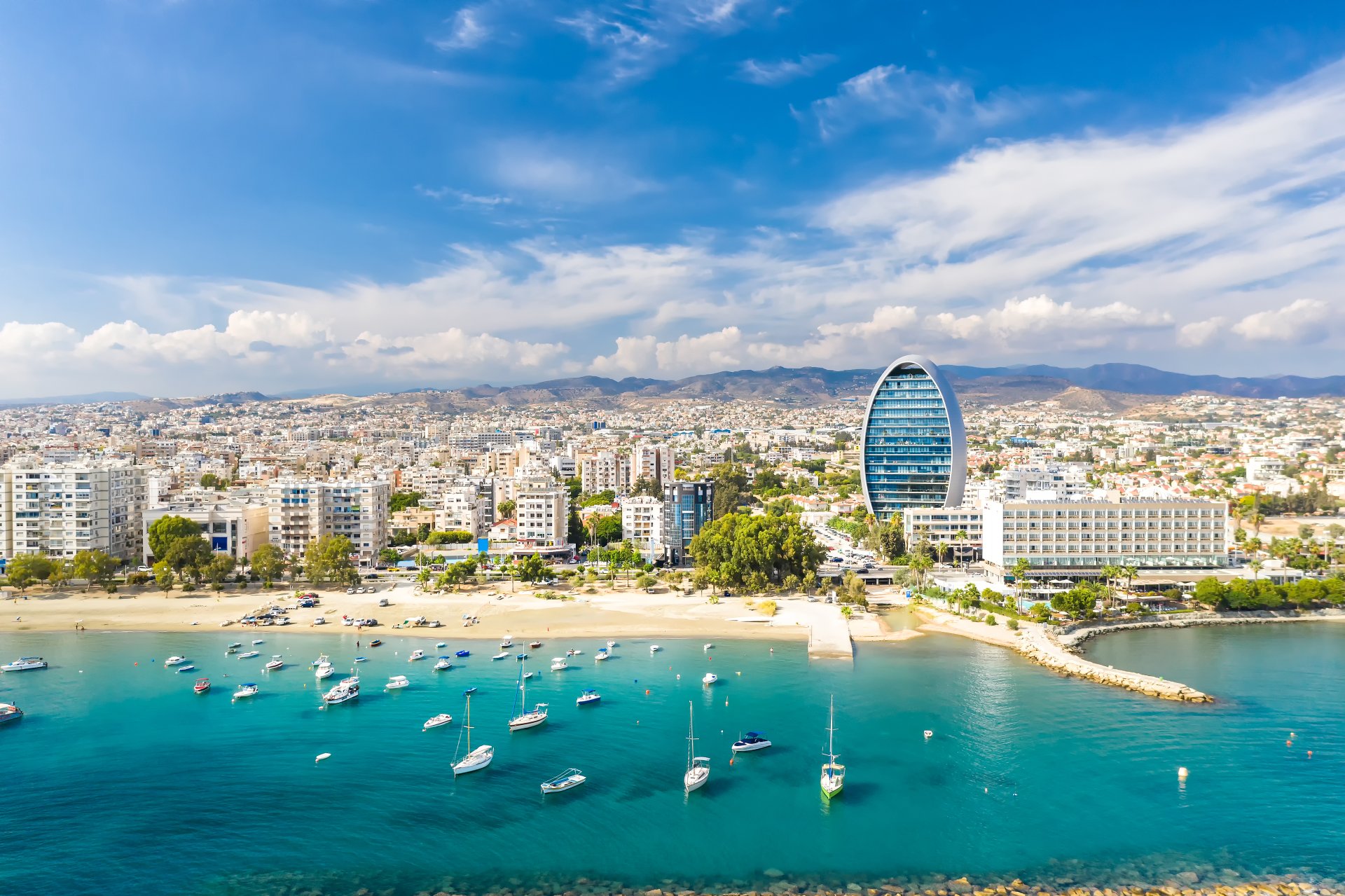 Vedere panoramica asupra orasului Limassol din Cipru, cu cladiri moderne langa litoral, mare albastra si zona de coasta luminata de soare, atmosfera calma de vara mediteraneana