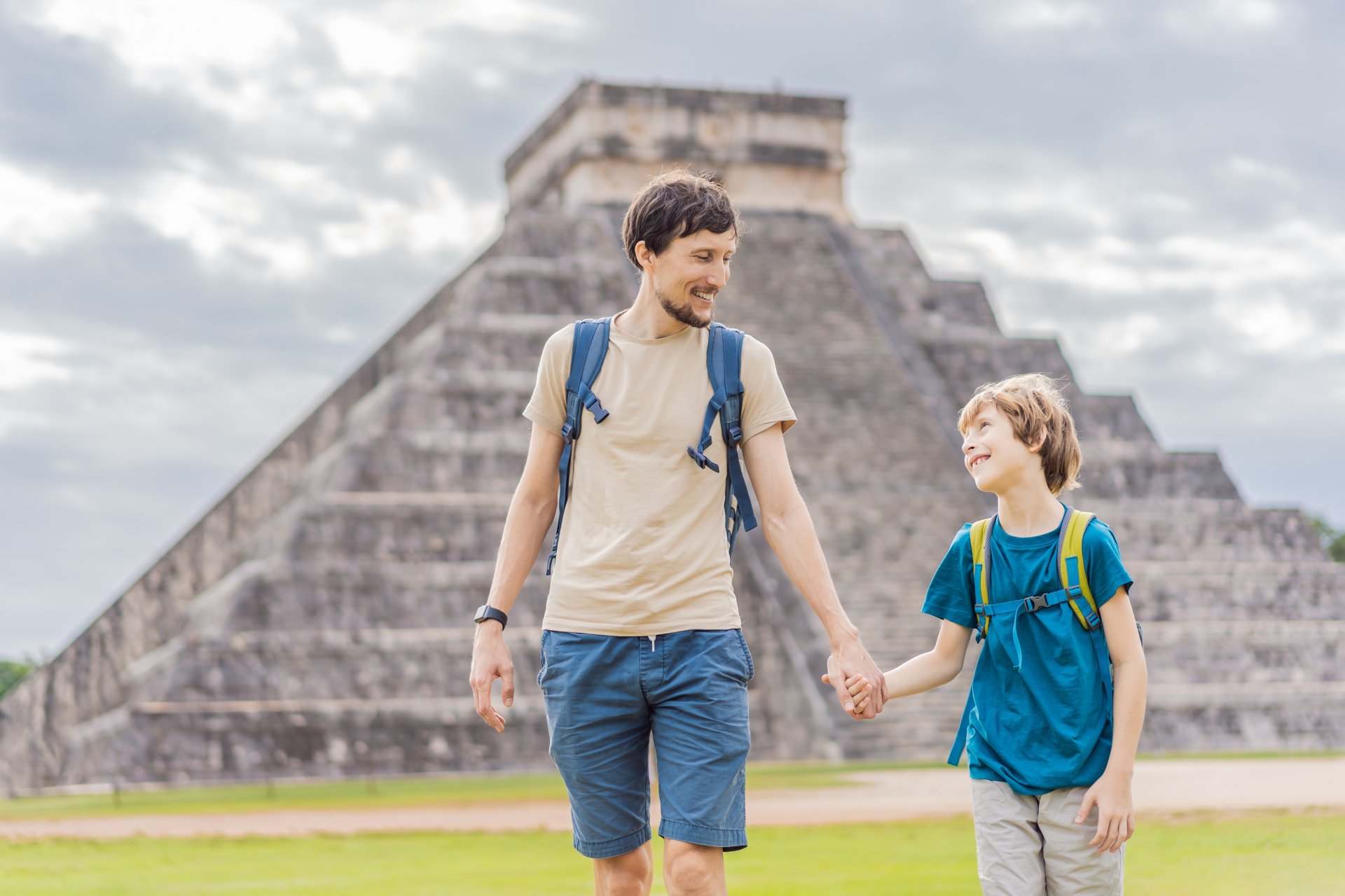 Tata si fiu turisti observa piramida si templul vechi din Chichen Itza, parte a civilizatiei pre-columbiene Maya