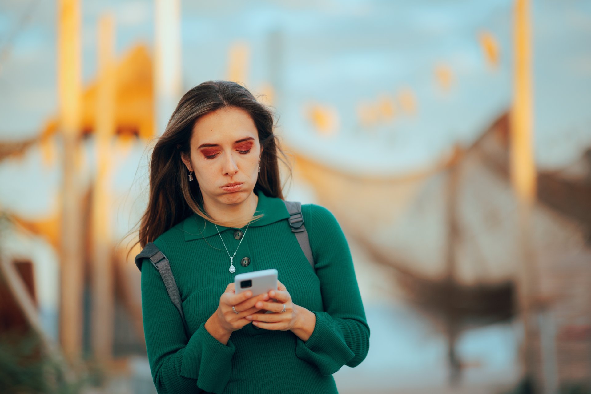 O turista merge singura pe o plaja si verifica telefonul mobil, avand o expresie ingrijorata, in timp ce incearca sa se orienteze intr-o destinatie necunoscuta.