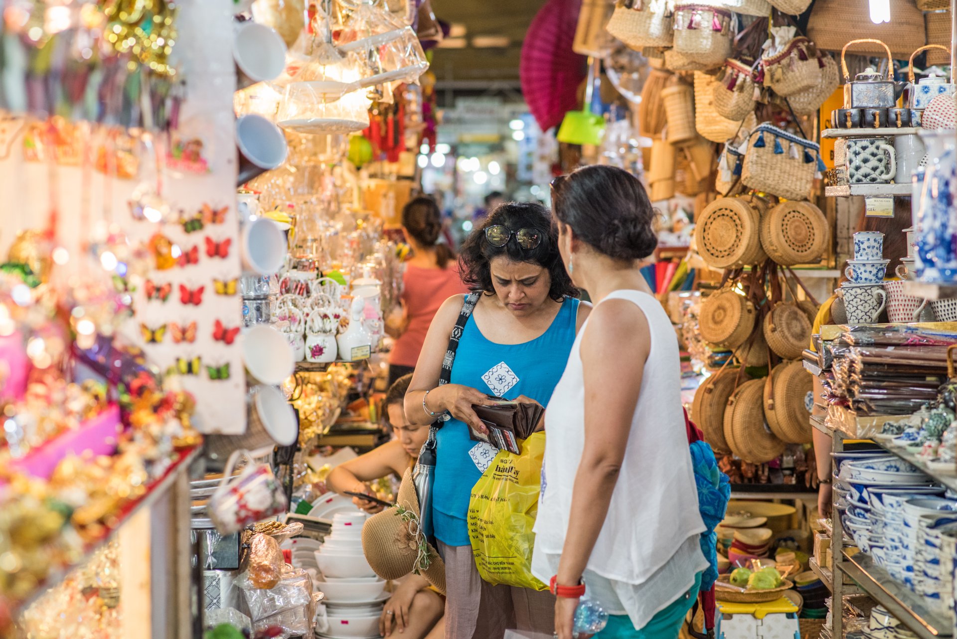 Doua turiste cumpara suveniruri in piata Ben Thanh din Ho Chi Minh si verifica banii din portofel