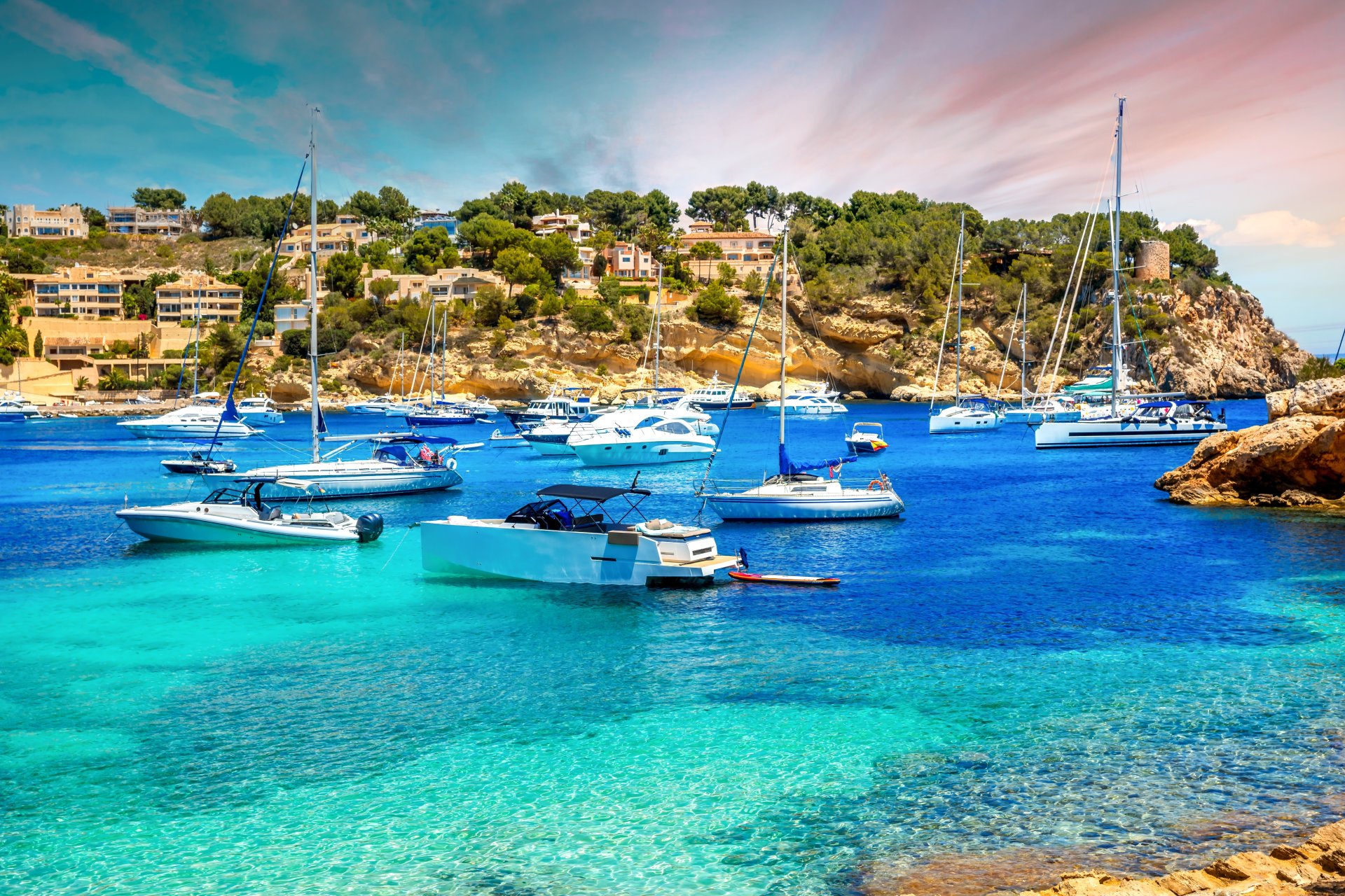 Peisaj de coasta la Portals Vells in Mallorca, cu apa turcoaz, stanci si vegetatie mediteraneana intr-o zi insorita din Spania.