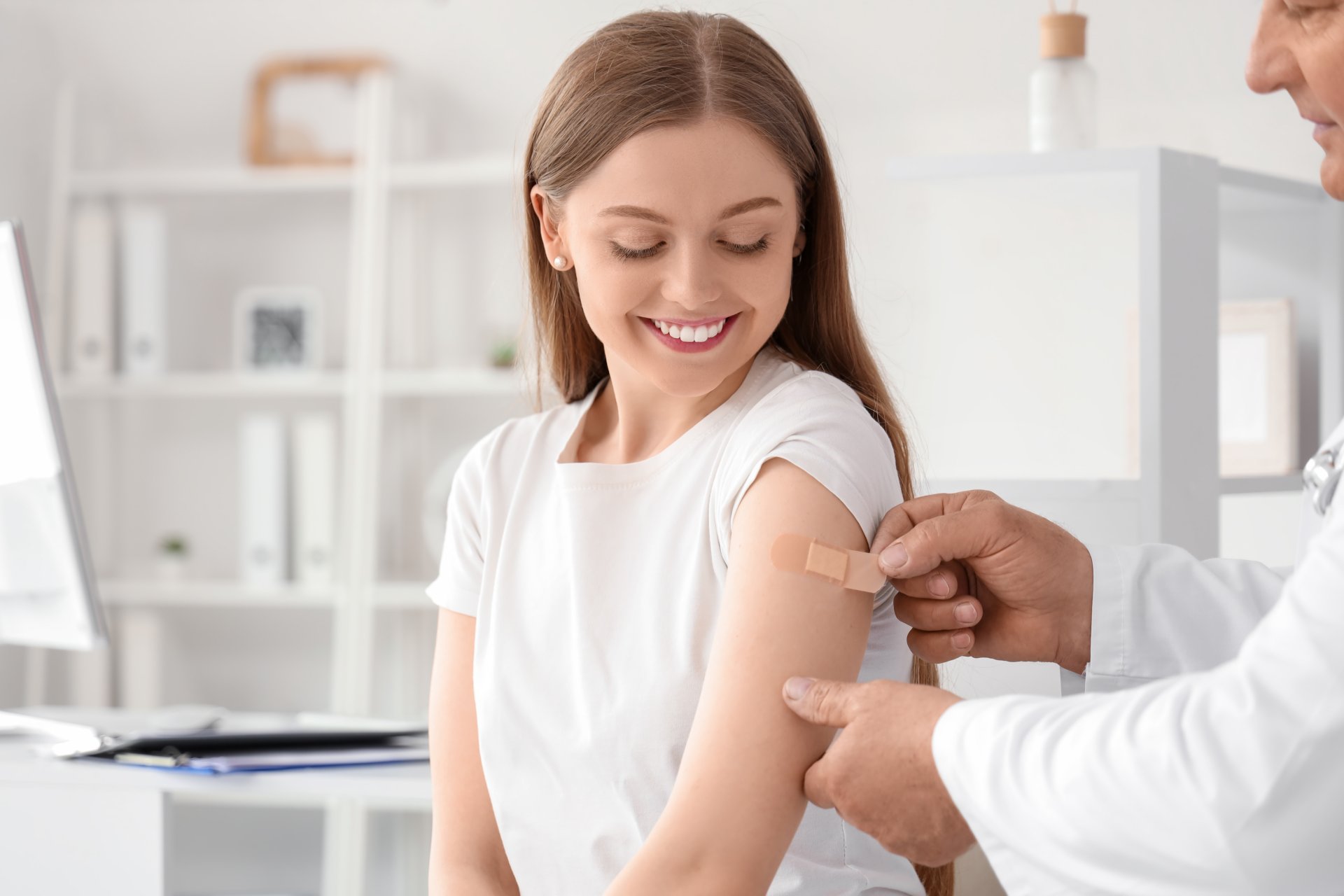 femeie tanara aplica un plasture dupa vaccinare intr-o clinica