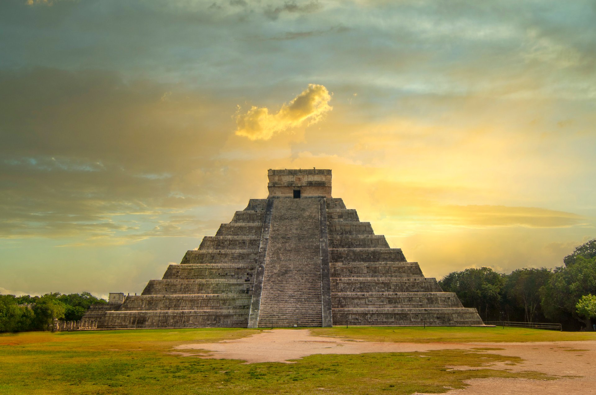Piramida principală de la Chichén Itzá, Mexico, iluminată de apusul spectaculos, cu umbre dramatice și cer portocaliu în fundal