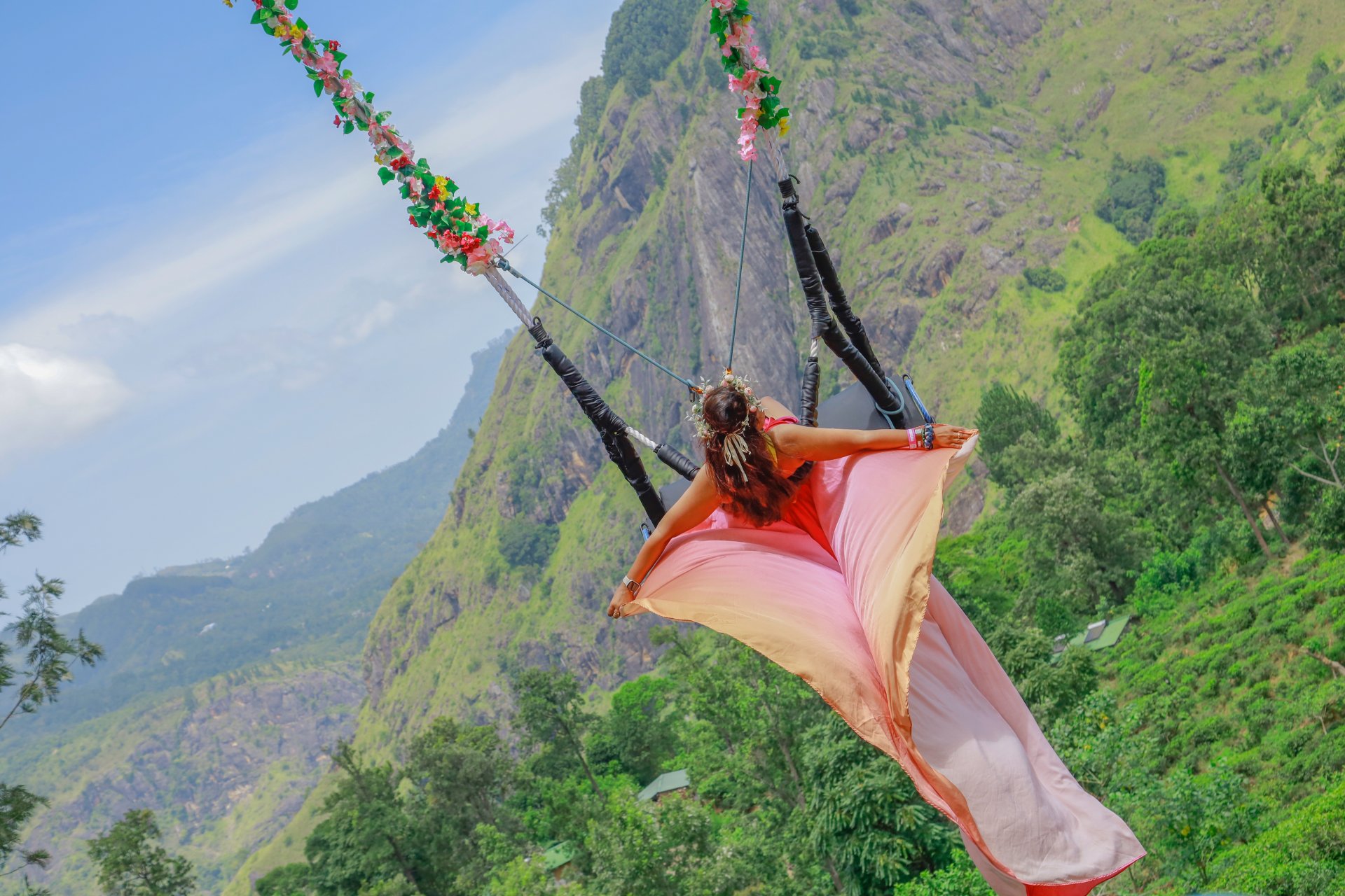 turista pe un leagan suspendat deasupra plantatiilor de ceai din Ella Sri Lanka la Ravana Pool Club cu priveliste asupra dealurilor verzi si ceata usoara de dimineata