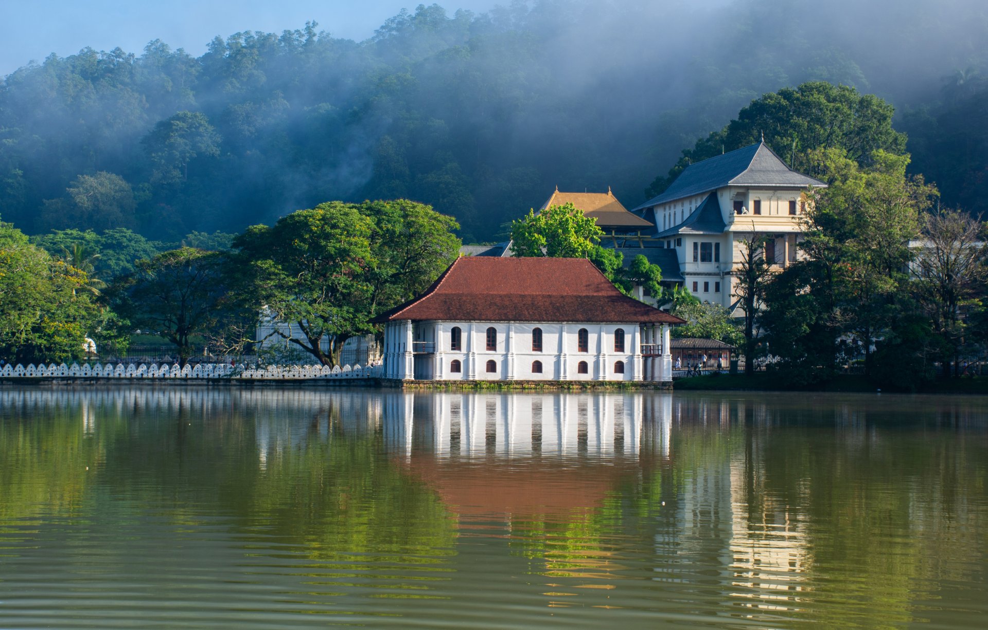 templul budist dalada maligawa din kandy sri lanka vazut din exterior cu arhitectura traditionala alba si aurie si vizitatori in curtea complexului regal