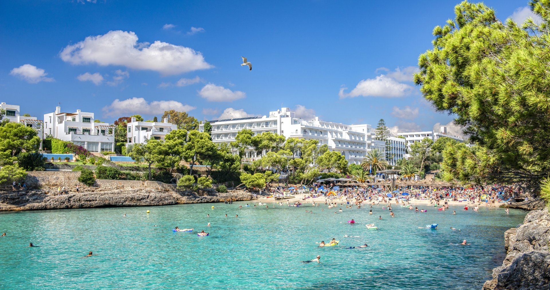 turisti care se bucura de o baie in mare in zona Cala d’Or din Mallorca, apa turcoaz si plaja cu nisip fin, atmosfera de vara relaxata si soare puternic in Spania