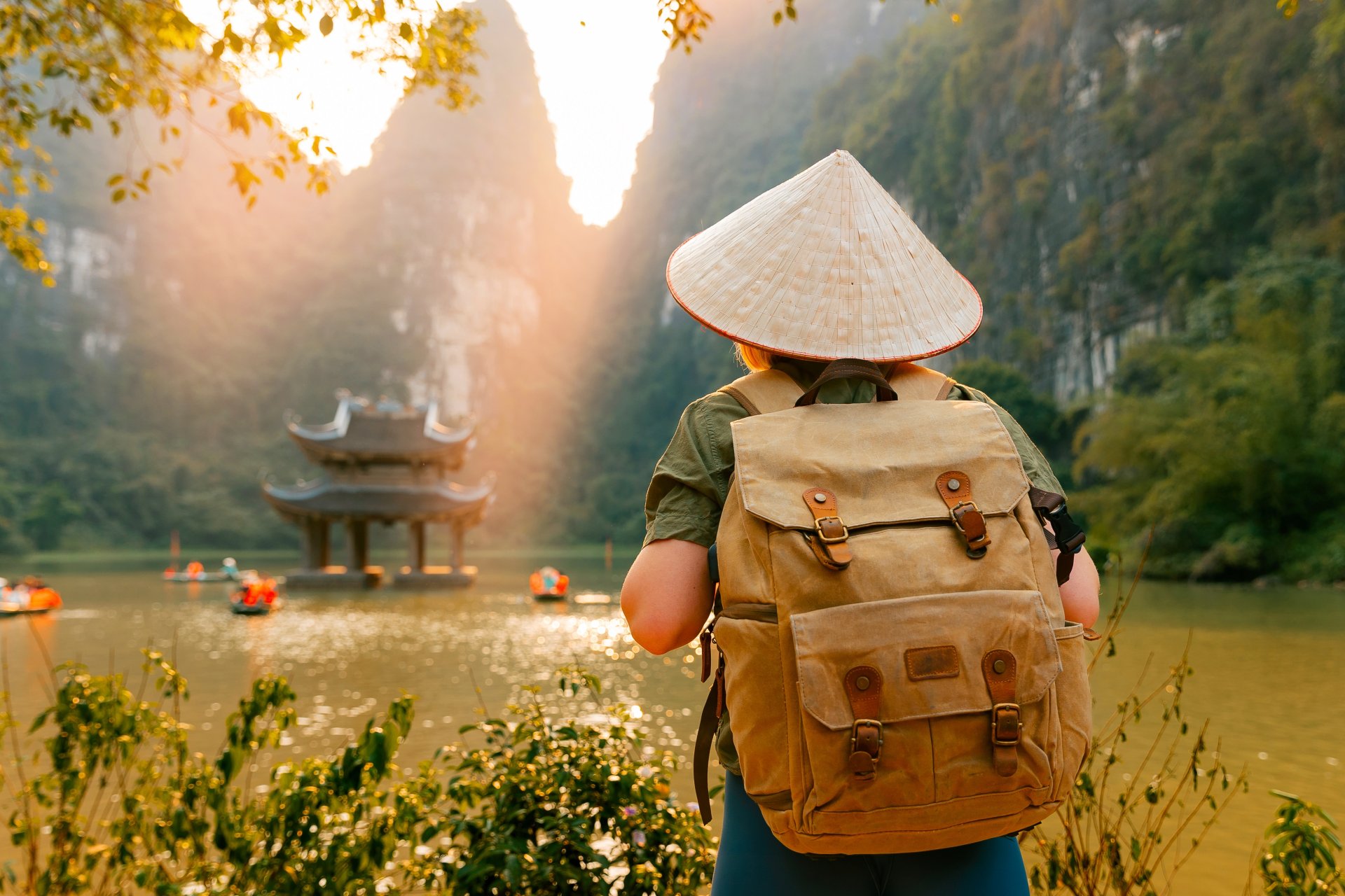explorand ninh binh o femeie calator cu rucsac si palarie conica la un râu pitoresc cu pagoda