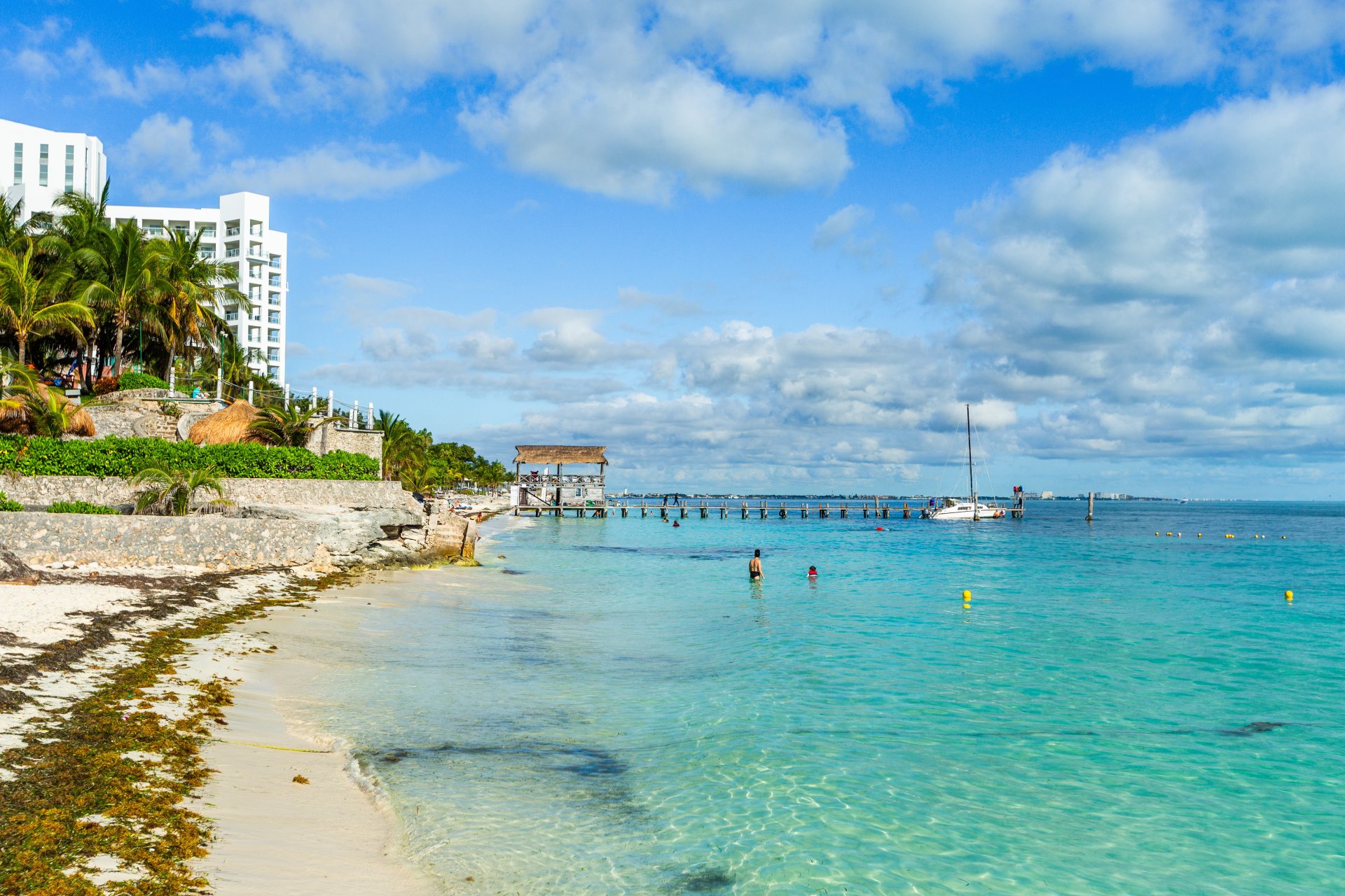 Plajă cu nisip alb și apă turcoaz la Playa Tortugas, Cancun, cu catamarane ancorate și atmosfera tropicală vibrantă din apropierea hotelurilor
